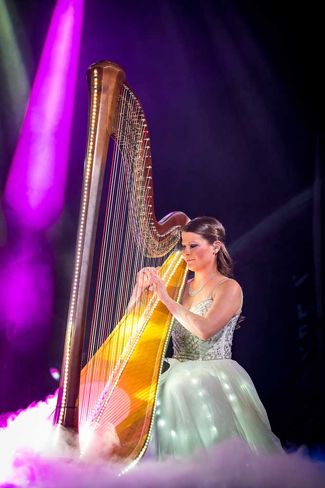 Catherine Haygood playing harp amid stage lights and fog