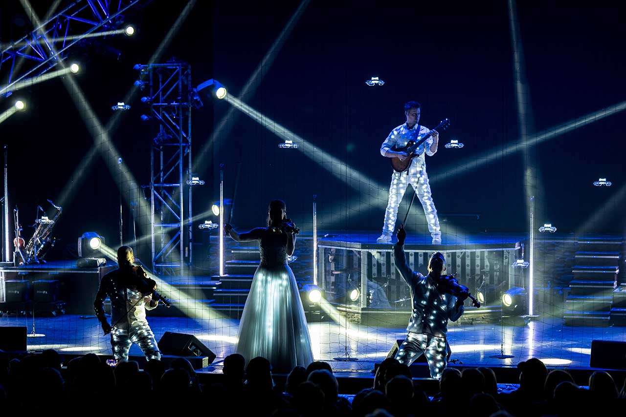 The Haygoods performing among beams of light and illuminated drones
