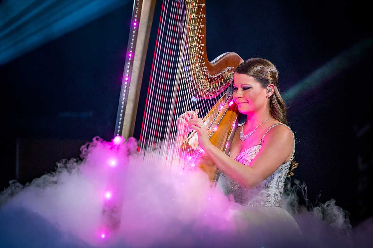 Catherine Haygood performing on an illuminated harp amid pink fog